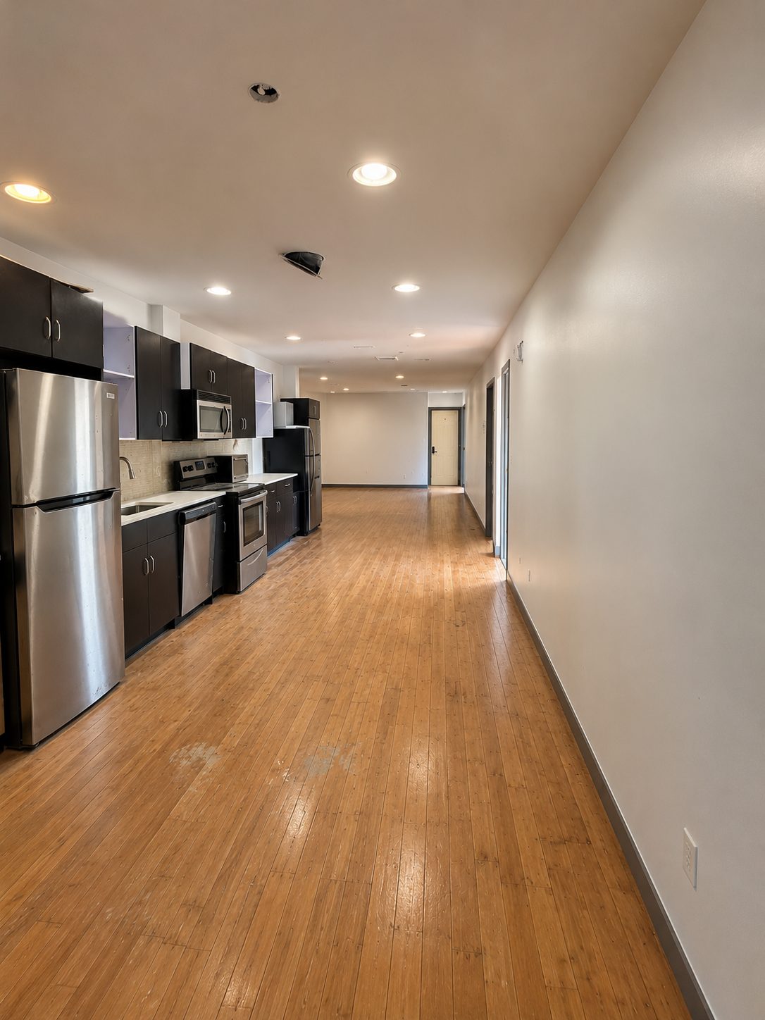 Actual photo of the kitchen with dark cabinets, stainless steel appliances and hardwood floors
